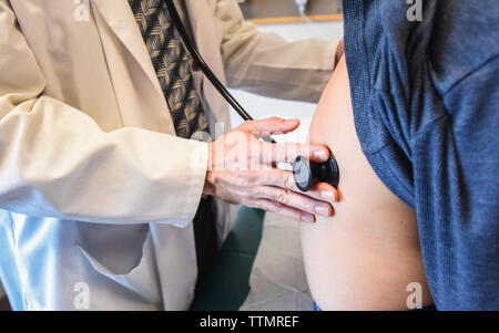Der Arzt untersucht den Patienten mit einem Stethoskop in einer Klinik. Stockfoto