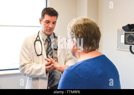 Arzt Untersuchung der Hand eines älteren Patienten in einer klinischen Einrichtung. Stockfoto