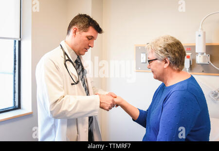 Arzt prüft die Hand des älteren Patienten in einer klinischen Einrichtung. Stockfoto