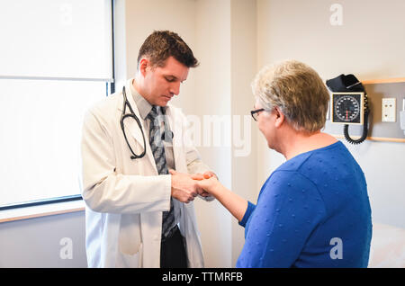 Arzt prüft die Hand des älteren Patienten in einer klinischen Einrichtung. Stockfoto