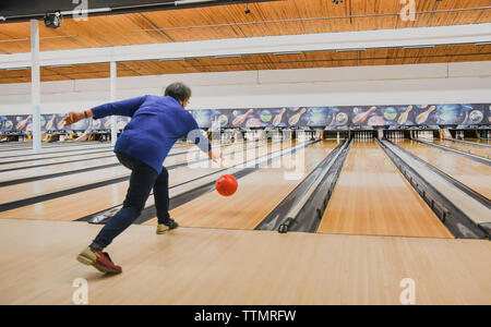 Ältere Frau werfen Bowling Kugel unten eine Bowlingbahn. Stockfoto