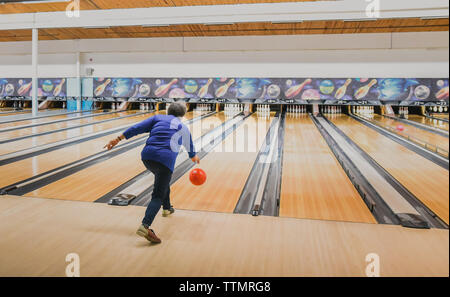 Ältere Frau werfen Bowling Kugel unten eine Bowlingbahn. Stockfoto