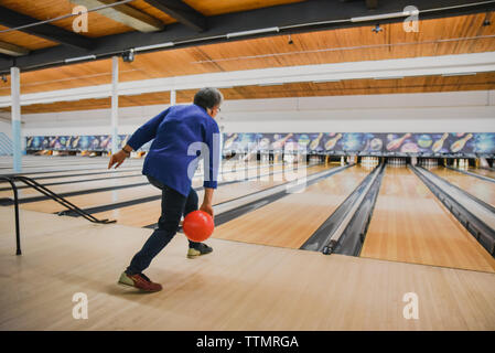 Ältere Frau werfen Bowling Kugel unten eine Bowlingbahn. Stockfoto