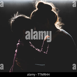 Hintergrundbeleuchtung Portrait von Mutter und Sohn mit Köpfe zusammen lächeln. Stockfoto