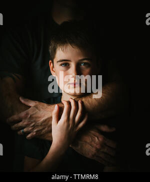 Close up Portrait eines Jungen mit der Waffe seines Vaters um ihn herum gewickelt. Stockfoto