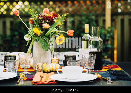 Vase mit Ort- und Weinflaschen am Esstisch im Hinterhof Stockfoto