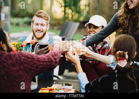 Gerne Freunde toasten Getränke, während im Hinterhof sitzen Stockfoto