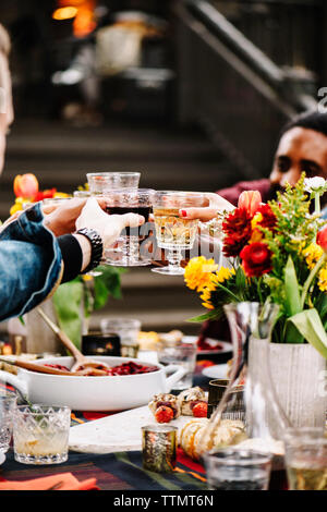 Freunde toasten Wein beim Sitzen am Tisch im Hinterhof Stockfoto