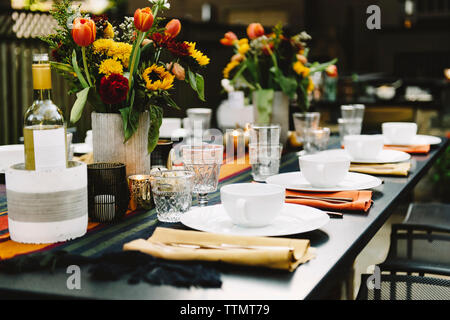 Blumenvasen mit Geschirr auf dem Tisch im Hinterhof angeordnet Stockfoto