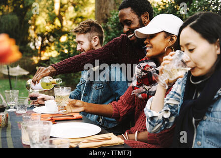 Glückliche Menschen gießen Wein an Freund im Hinterhof Stockfoto