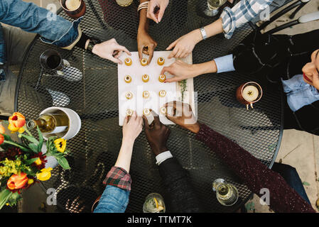Zugeschnittenes Bild Freunde unter Vorspeise beim Sitzen am Tisch im Hinterhof Stockfoto
