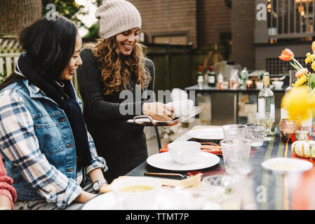 Gerne Frau Kürbissuppe mit Freunden am Tisch sitzen im Hinterhof Stockfoto