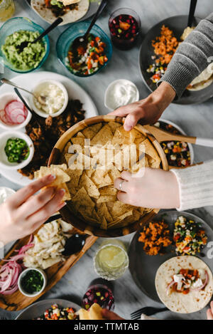 Ansicht von oben von Freunden, Nacho Chips beim Essen am Tisch während der Veranstaltung Stockfoto