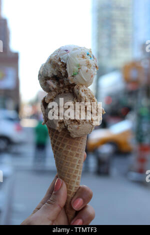 7/8 Hand der Frau mit Eis in der Stadt Stockfoto