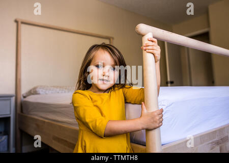 Mädchen lächelnd im gelben Kleid stehen, Bett im Schlafzimmer Stockfoto