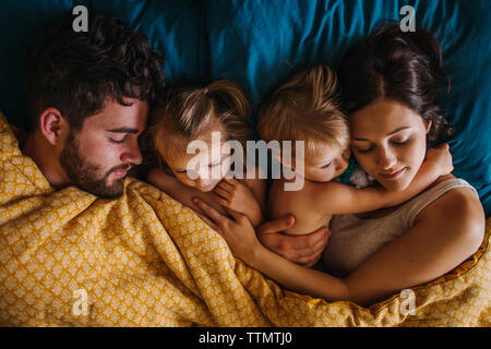 Familie von vier Kuscheln im Bett mit Kindern Stockfoto