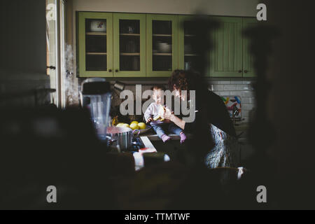 Junge Mädchen sitzen auf der gramma Küche essen Bananne Stockfoto