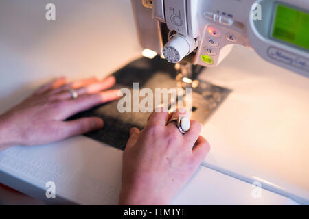 Zugeschnittenes Bild der weiblichen mit nähmaschine am Tisch in der Werkstatt zugeschnitten Stockfoto