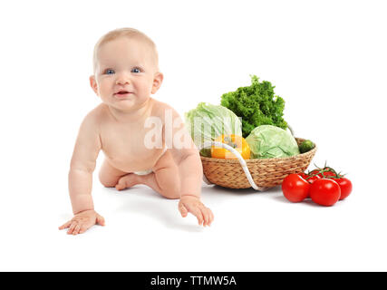 Cute Baby und frisches Gemüse in Weidenkorb auf weißem Hintergrund Stockfoto