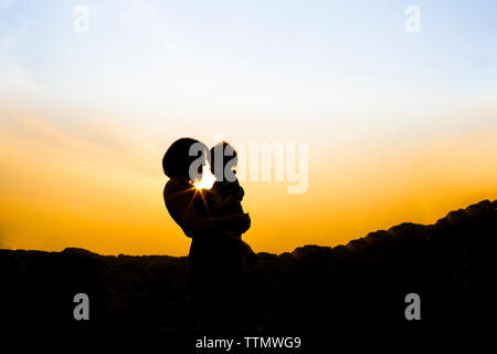 Silhouette Mutter mit Sohn beim Stehen in der Park gegen Himmel bei Sonnenuntergang Stockfoto