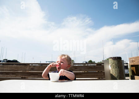 Kleinkind Junge isst Eis vor einem blauen Himmel in Oxford, Maryland Stockfoto