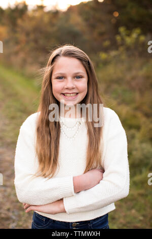Das Lächeln der 13 Jahre alte Mädchen steht selbstbewusst bei Sonnenuntergang auf der Spur Stockfoto