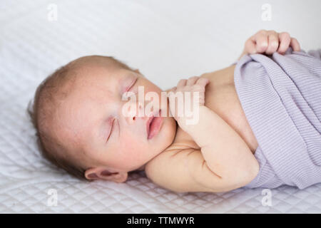 Schlafen neugeborene Baby Mädchen in Lila Decke auf weißen Bett Stockfoto