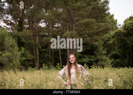 Weitwinkel von Zuversichtlich, Lächeln, jugendlich Mädchen stehen im grünen Feld Stockfoto