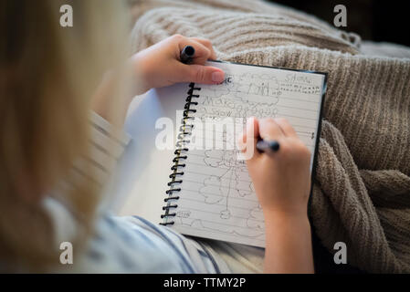 Hohe Betrachtungswinkel von Mädchen schreiben in Tagebuch während zu Hause sitzen Stockfoto