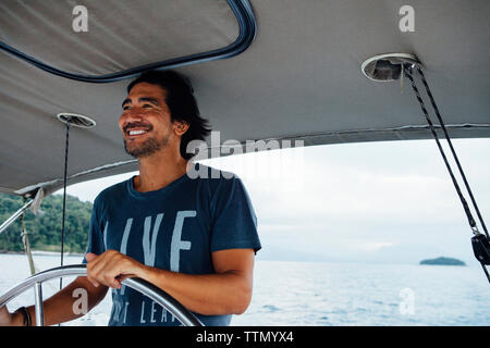 Glückliche Menschen Wegschauen während Segelboot auf das Meer Stockfoto