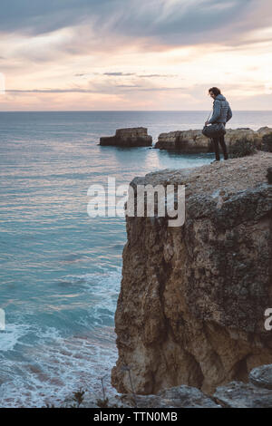 Man Blick auf das Meer beim Stehen auf Klippe gegen Himmel bei Sonnenuntergang Stockfoto