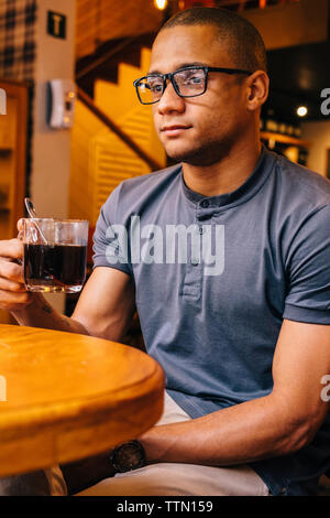 Nachdenklichen jungen Mann mit schwarzen Kaffee weg schauen im Cafe Stockfoto