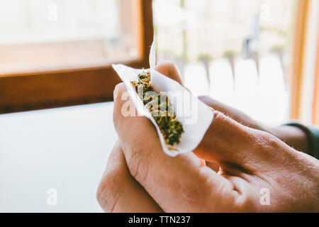 7/8 der Menschen Hand rolling Marihuana Gelenke in Papier zu Hause Stockfoto