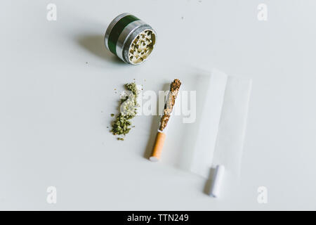 Ansicht von oben von Marihuana Gelenke, Zigarette mit Papier und Schleifer auf weißen Tisch Stockfoto