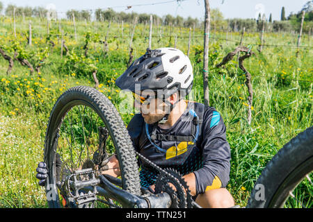 Junger Mann Instandsetzung Mountainbike auf Feld Stockfoto