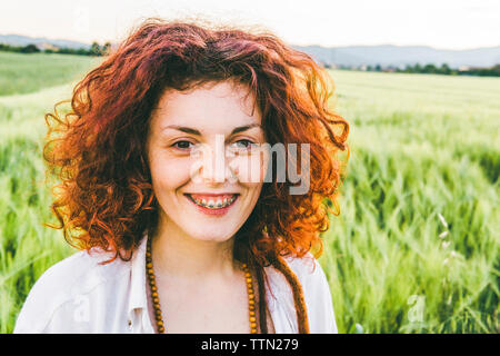Porträt der lächelnde Frau mit redhead stehend an Farm gegen Sky Stockfoto