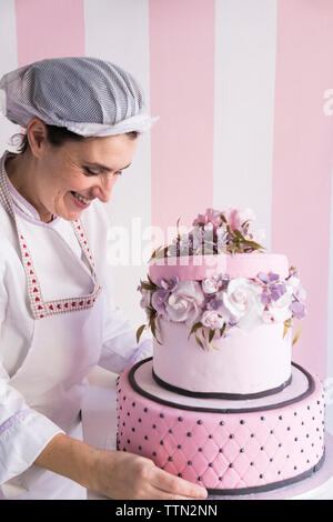 Lächelnd weibliche Baker einstellen Kuchen auf gegen die Wand im Labor Stockfoto