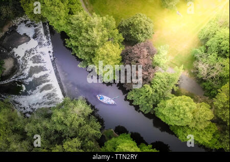 Luftaufnahme von einer schönen grünen Wald mit einem schönen Wasserfall und ein Boot segeln im Fluss Stockfoto