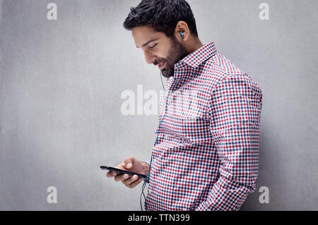 Mitte der erwachsene Mann texting und Hören von Musik Stockfoto