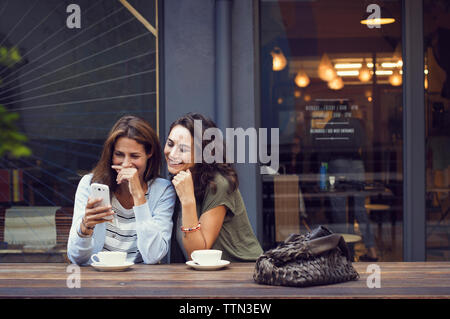 Gerne reife Frauen mit Smart Phone auf Sidewalk Cafe Stockfoto