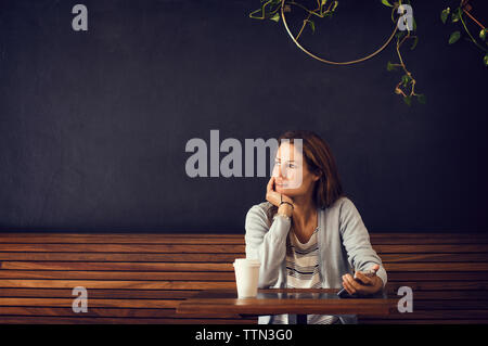 Nachdenkliche Frau weg, während im Cafe sitzen Stockfoto