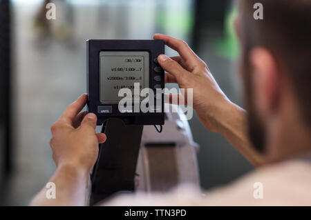 Zugeschnittenes Bild des Athleten mit Monitor am Rudergerät in der Turnhalle Stockfoto