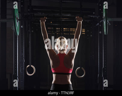 Ansicht der Rückseite des weiblichen Athleten Kommissionierung barbell im Fitnessstudio Stockfoto