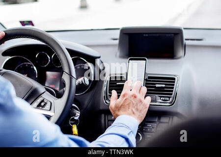 Zugeschnittenes Bild der Geschäftsmann Sie GPS auf Smartphones im Auto. Stockfoto