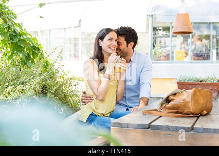 Gerne Frau mit Saft Glas beim Sitzen mit Mann an Sidewalk Cafe Stockfoto