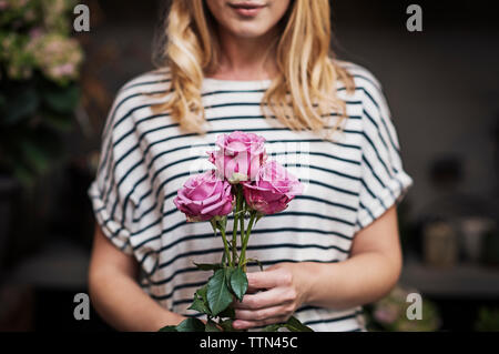 Mittelteil der Frau mit rosa Rosen in Flower Shop Stockfoto
