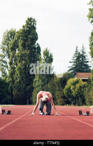Athlet am Startblock auf Schiene balanciert Stockfoto