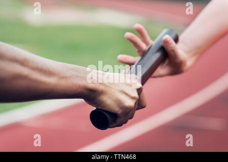 Zugeschnittenes Bild von Runner vorbei Baton Mannschaftskamerad Stockfoto