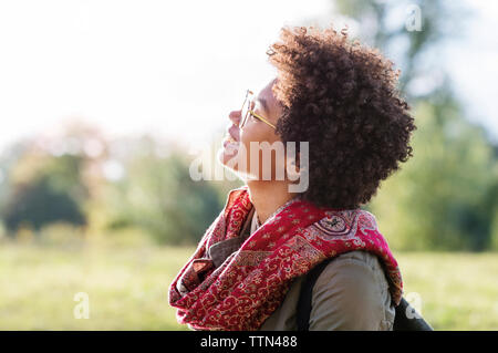 Nachdenklich lächelnde Frau mit Kopftuch stehend an Feld Stockfoto