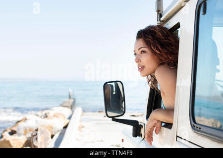 Frau spähen durch Auto Fenster am Strand während der sonnigen Tag Stockfoto